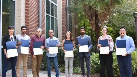 Aurora Tsai, Skanda Vivek, Mohammad Mofidfar, Abouzar Kaboudian, Jacqueline Palmer, Harish Ravichandar, Katalin Dosa, and Seung Yup “Paul” Lee show the awards they earned for their presentations at the 5th Annual Georgia Tech Postdoctoral Research Symposium on Sept. 20, 2018.