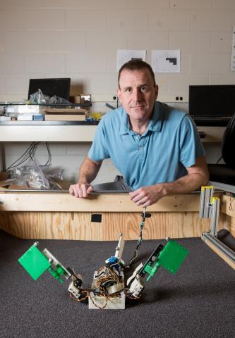 Dan Goldman, associate professor in the Georgia Tech School of Physics, is shown with the “MuddyBot” robot in a trackway used to study how the robot – which was modeled on the mudskipper fish – moved across granular surfaces. (Credit: Rob Felt, Georgia Tech)